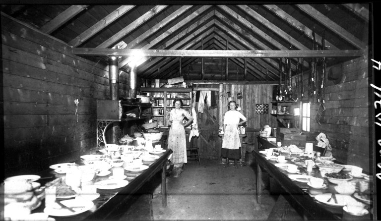 Two women stand in a cookhouse at Newcastle Mine in Drumheller Valley, ca. 1912; Newcastle was one of the first mine operations in Drumheller Valley to establish a cookhouse, which fed up to 100 miners three times a day. Source: Courtesy of Atlas Coal Mine National Historic Site 