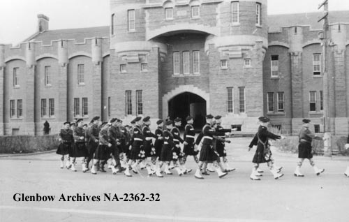 Calgary Highlanders pipe band parading by Mewata Armoury, Calgary, date unknown. (Glenbow Archives, NA-2362-32).