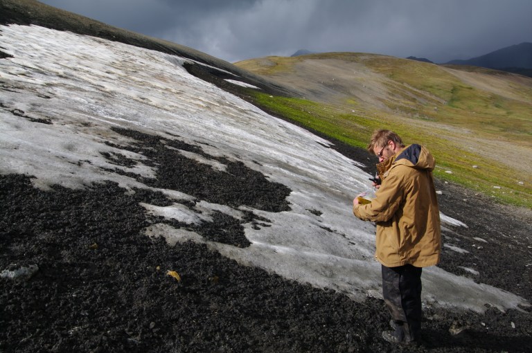 An archaeologist surveying a melting ice patch for artifacts (courtesy of Mike Donnelly).