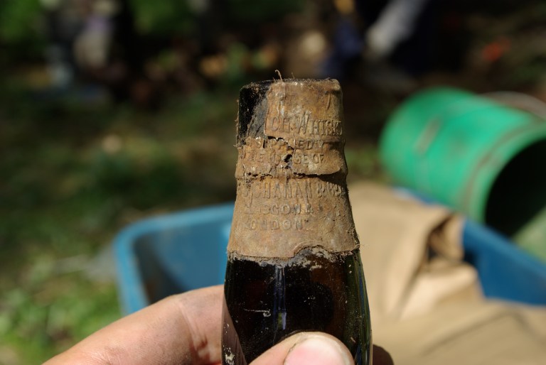 A liquor bottle with the label still on it was found at one of the private houses. The label indicates that the product was imported from the U.K. (Photo Credit: Lifeways of Canada Ltd.)