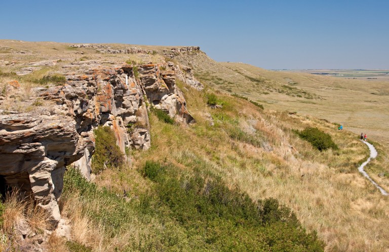 Figure 1. The sandstone cliffs at Head-Smashed-In are much shorter than in pre-contact times. Archaeologists have excavated through over 8 m of sediment and bone at the base of the cliff to reach the oldest layers of pre-contact hunting at Head-Smashed-In. Image courtesy of Alberta Culture and Tourism.