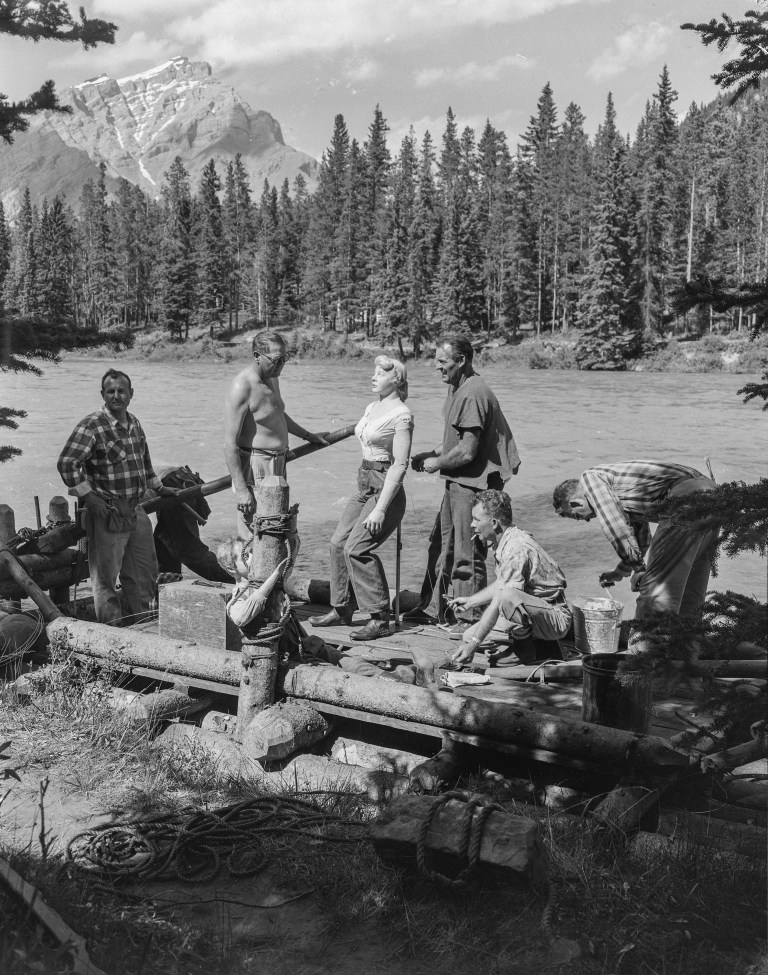 One of four wooden rafts used in the film 'River of No Return', filmed in Jasper and Banff in 1953. Notice the "stunt double dummies" standing in for film stars Marilyn Monroe and Robert Mitchum. (Photo Credit: Provincial Archives of Alberta PA3057.4)