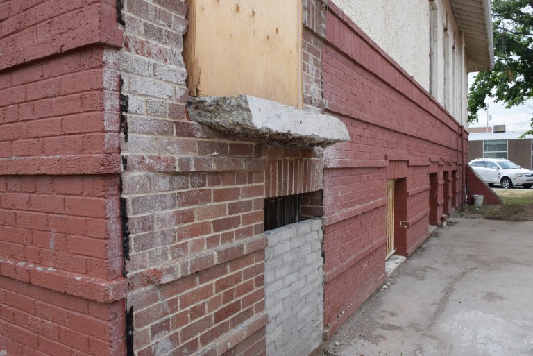 Unpainted masonry is exposed after the demolition of a large addition, previously used for the Town’s emergency services, connected to the historic building’s northwest corner. Areas like this are important evidence of earlier (and sometimes original) stucco colour and mortar joint profiles. Both the stucco and brick masonry exterior were painted. Source: Historic Resources Management Branch.