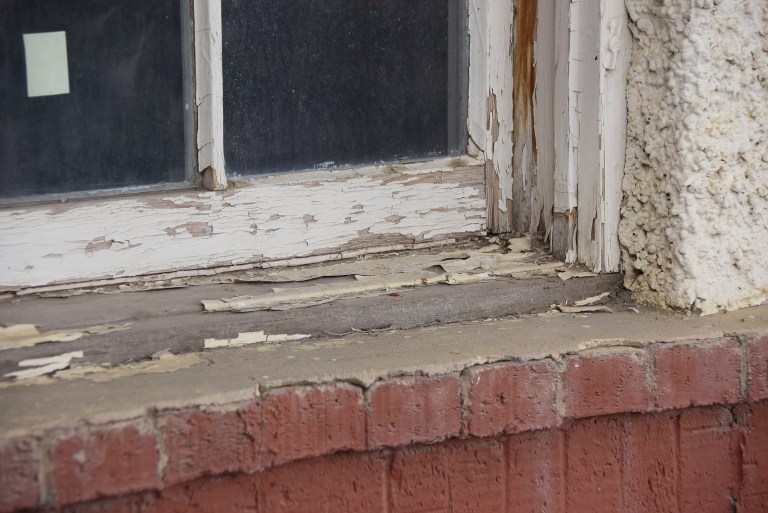 The sash and sill of an original window shows typical extensive paint failure, weathered wood, and glazing putty that was cracked, missing or repaired with caulking. The multi-pane windows were nearly all intact and are an important architectural feature and character-defining element. As is often the case in windy southern Alberta, the wood was dried and weathered with deep cracks or “checks” but showed little actual decay. Well-constructed windows of clear grain, old-growth fir are durable and resilient even after years without maintenance. With the right materials, repair skills and elbow grease, such windows can be restored to near-new condition. This retains an important historic element, conserves integrity, and keeps perfectly serviceable materials out of municipal landfills. Source: Historic Resources Management Branch.