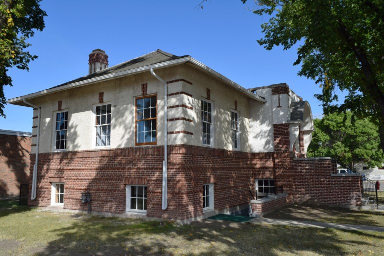 The courthouse after restoration of all exterior windows and the brick masonry. The stucco southeast stair enclosure was removed and the damaged original masonry pony wall rebuilt using physical evidence of the feature and original blueprints. The pony wall was rebuilt with salvaged original brick as a veneer over concrete block infill to make up for unsalvageable original brick. A precast concrete coping and steel railing were added to meet code. Source: Historic Resources Management Branch.