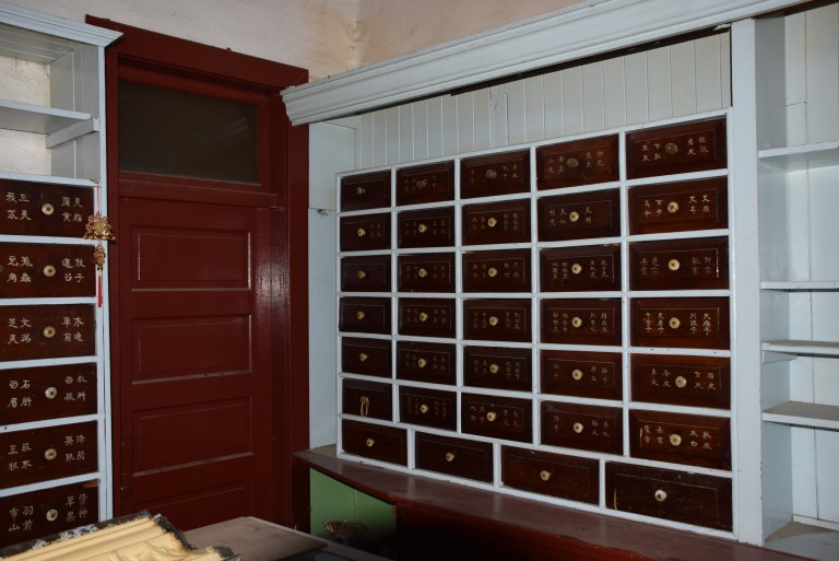 (Above) Interior photo showing main floor apothecary cabinets. Source: Historic Resources Management Branch, 2014. (Below) Chinese medicines stores in apothecary cabinets. Source: Historic Resources Management Branch, 2014.